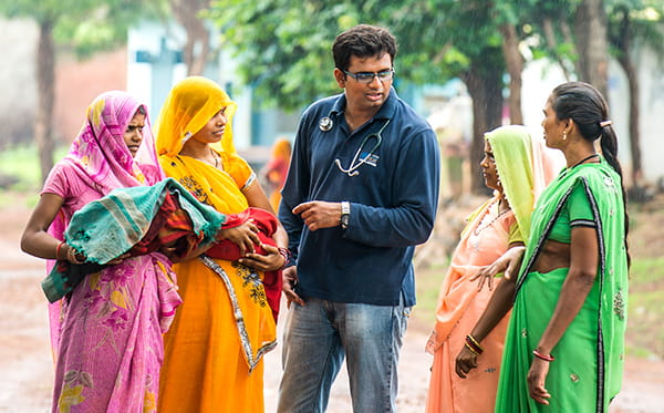 Dr. Sanket Patel talking to Indian women in colourful dresses